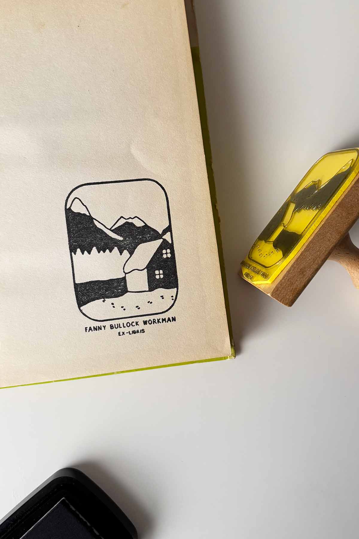 Portadilla de libro estampada con un paisaje con un chalet nevado y una montaña en el fondo y sello