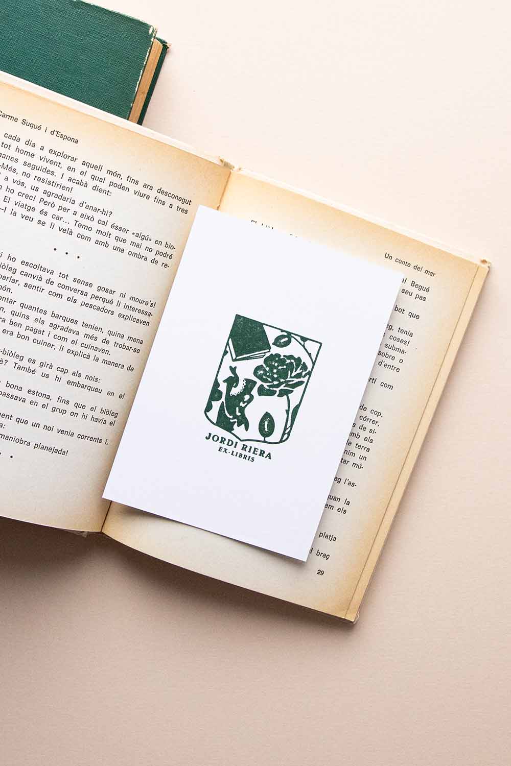 Portadilla de libro estampada con sello exlibris de un escudo con una rosa, un libro y un dragón