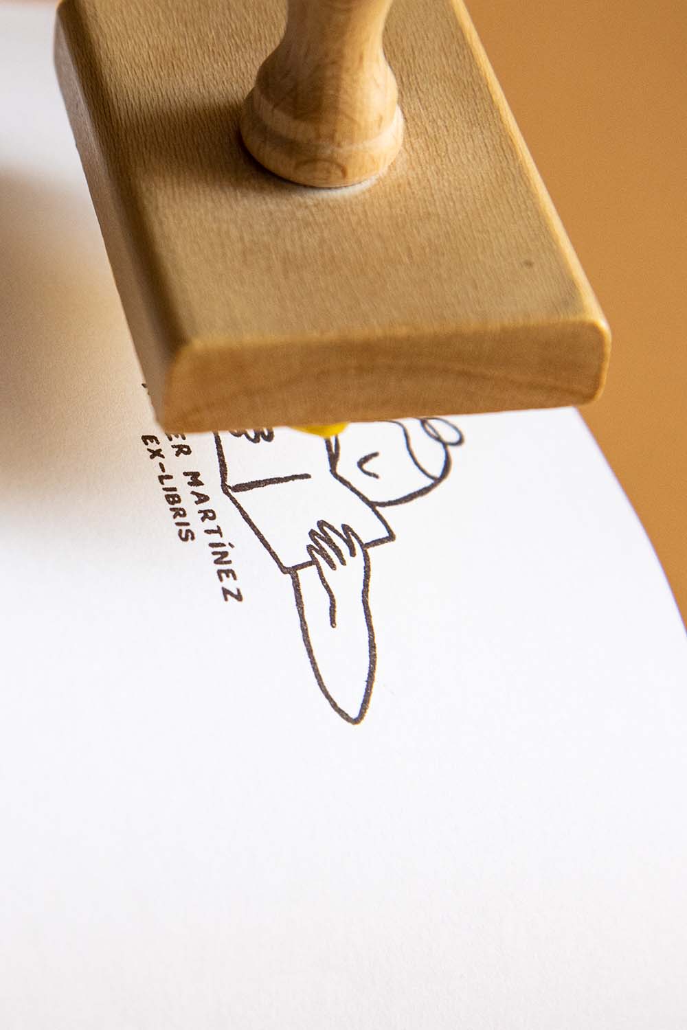 Portadilla de libro estampada con una lectora absorta en la lectura de un libro y sello