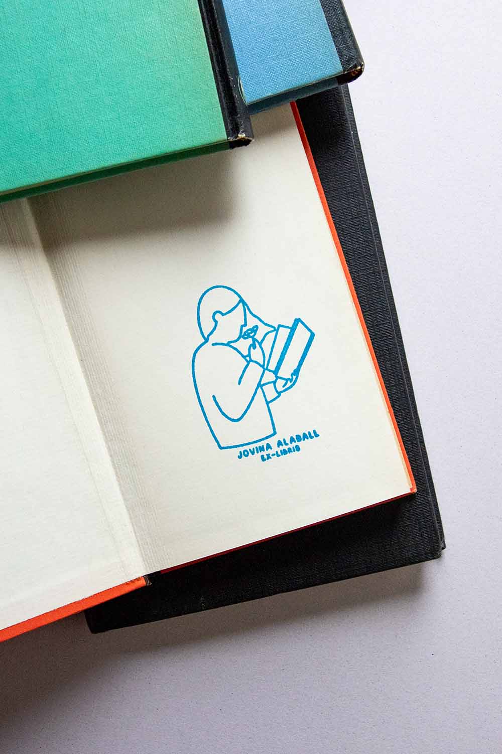 Portadilla de libro estampada con una lectora leyendo y oliendo una rosa