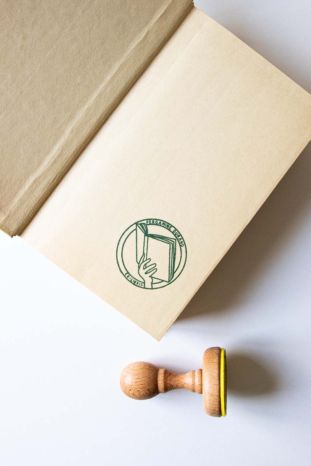 Portadilla de libro estampada con una mano sosteniendo un libro y sello