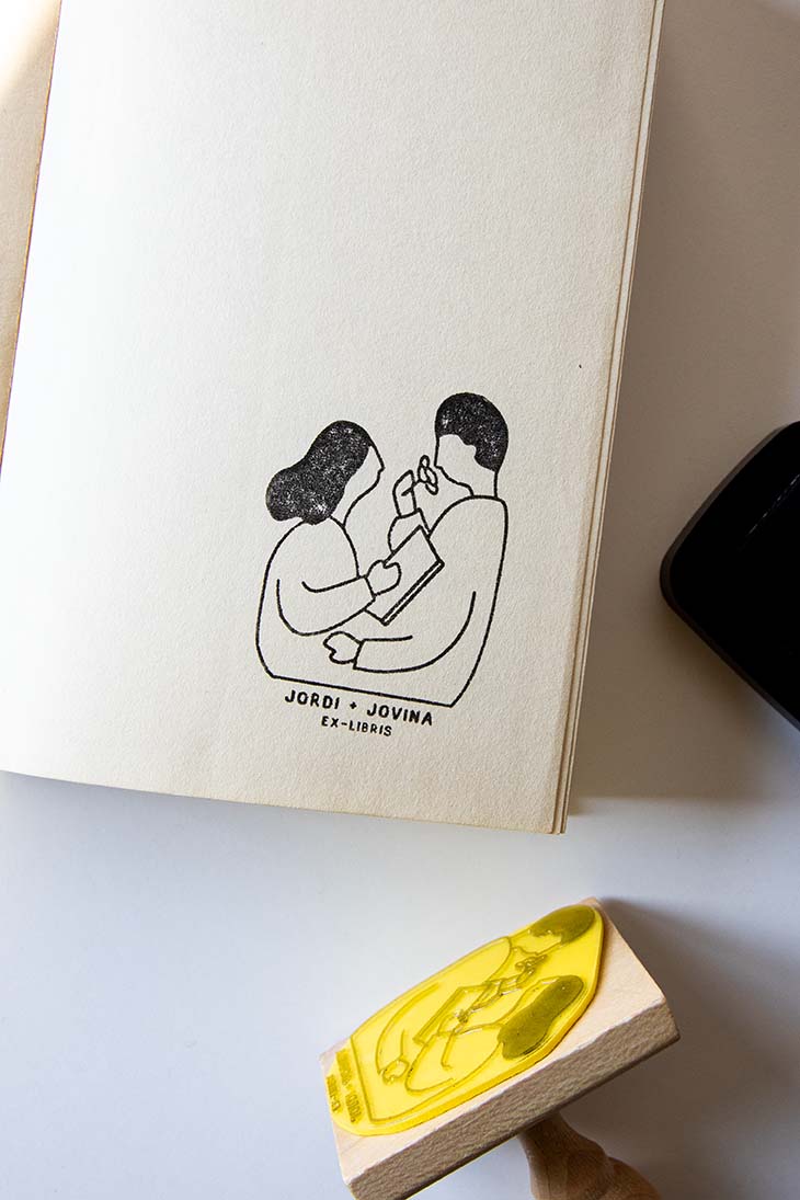 Portadilla de libro estampada con una pareja leyendo y oliendo una rosa y sello