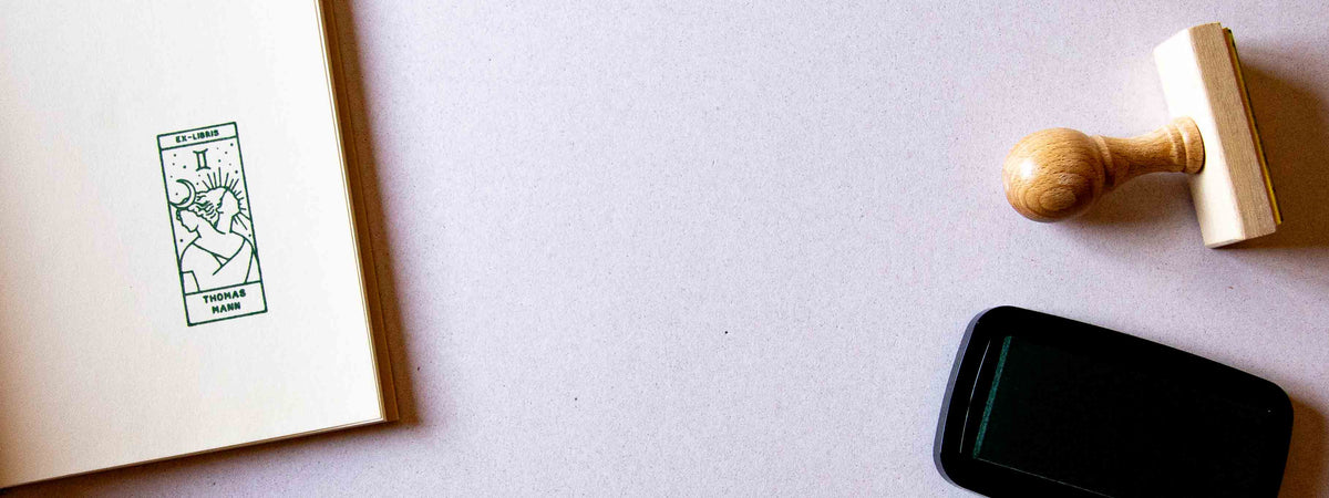 Exlibris personalizzato timbrato sulla pagina di guardia di un libro aperto, con il segno zodiacale dei Gemelli