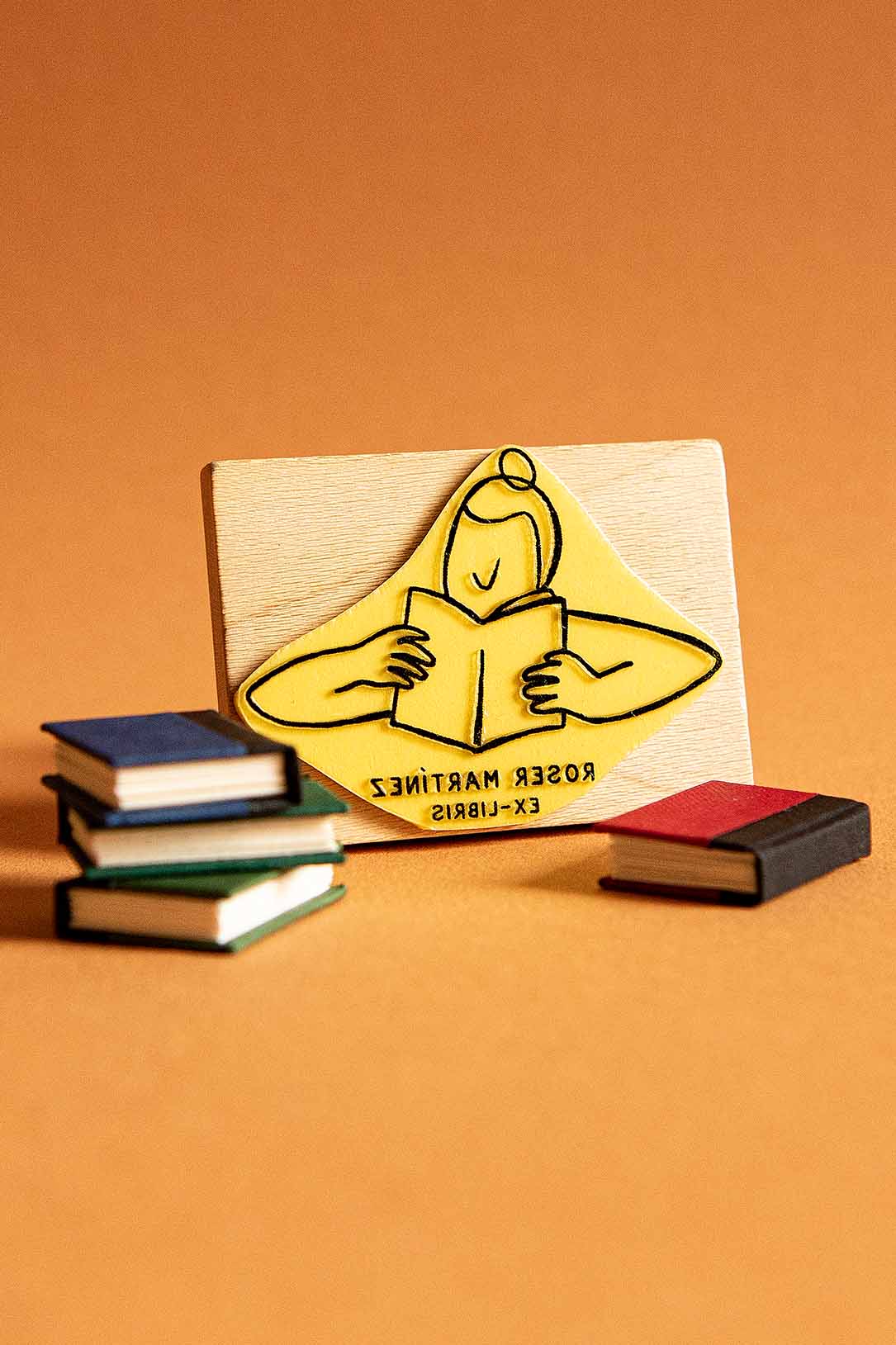 Sello exlibris grabado de una lectora absorta en la lectura de un libro