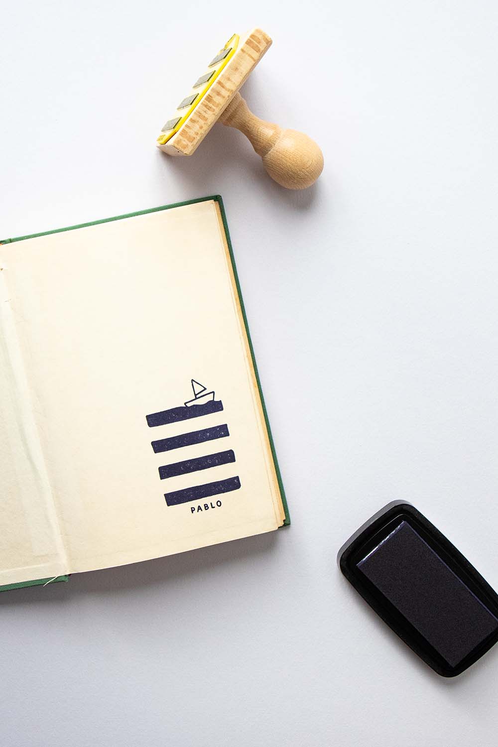 Portadilla de un libro estampada con un barquito de papel navegando y sello