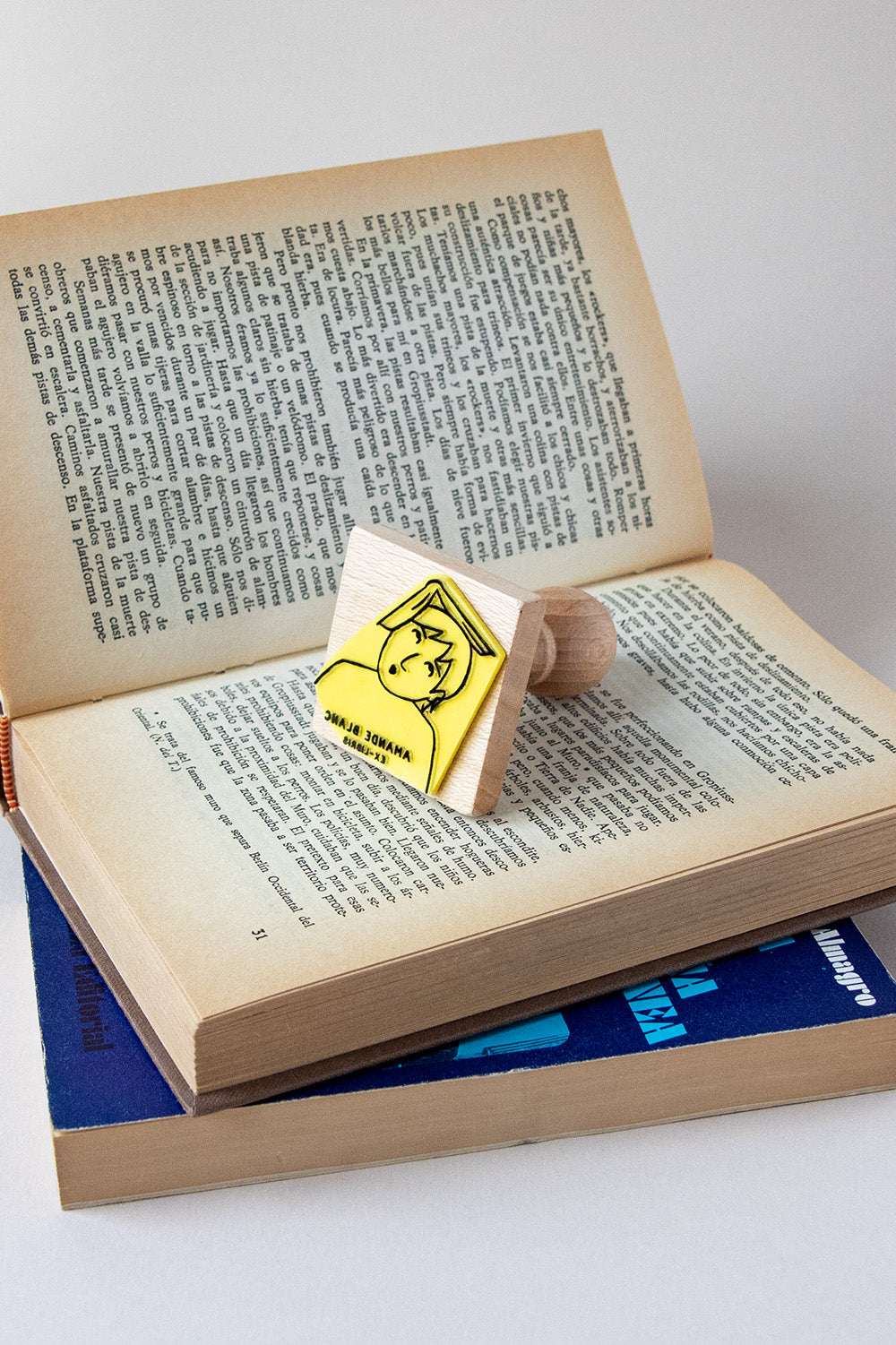 Sello exlibris grabado de una lectora sorprendida con un libro abierto en la cabeza