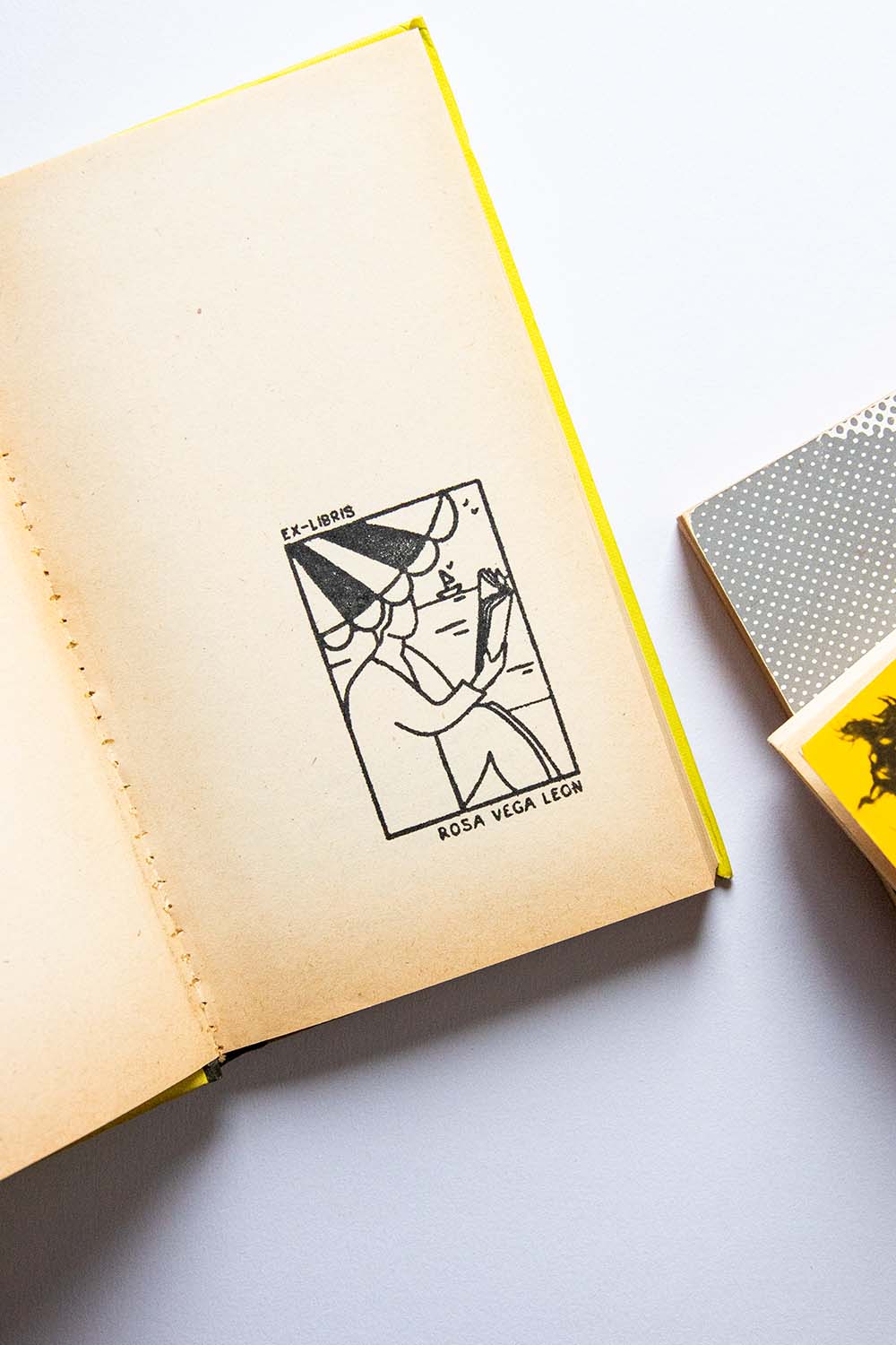 Portadilla de un libro estampada con una persona leyendo bajo la sombrilla en la playa