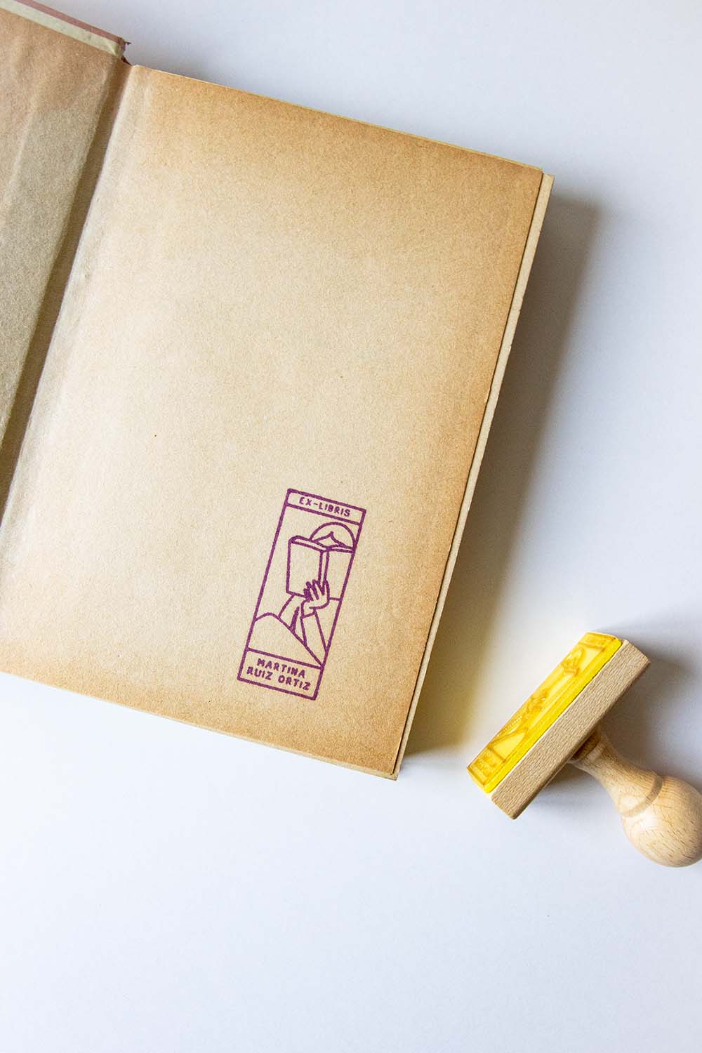 Portadilla de libro estampada con una persona leyendo y sello