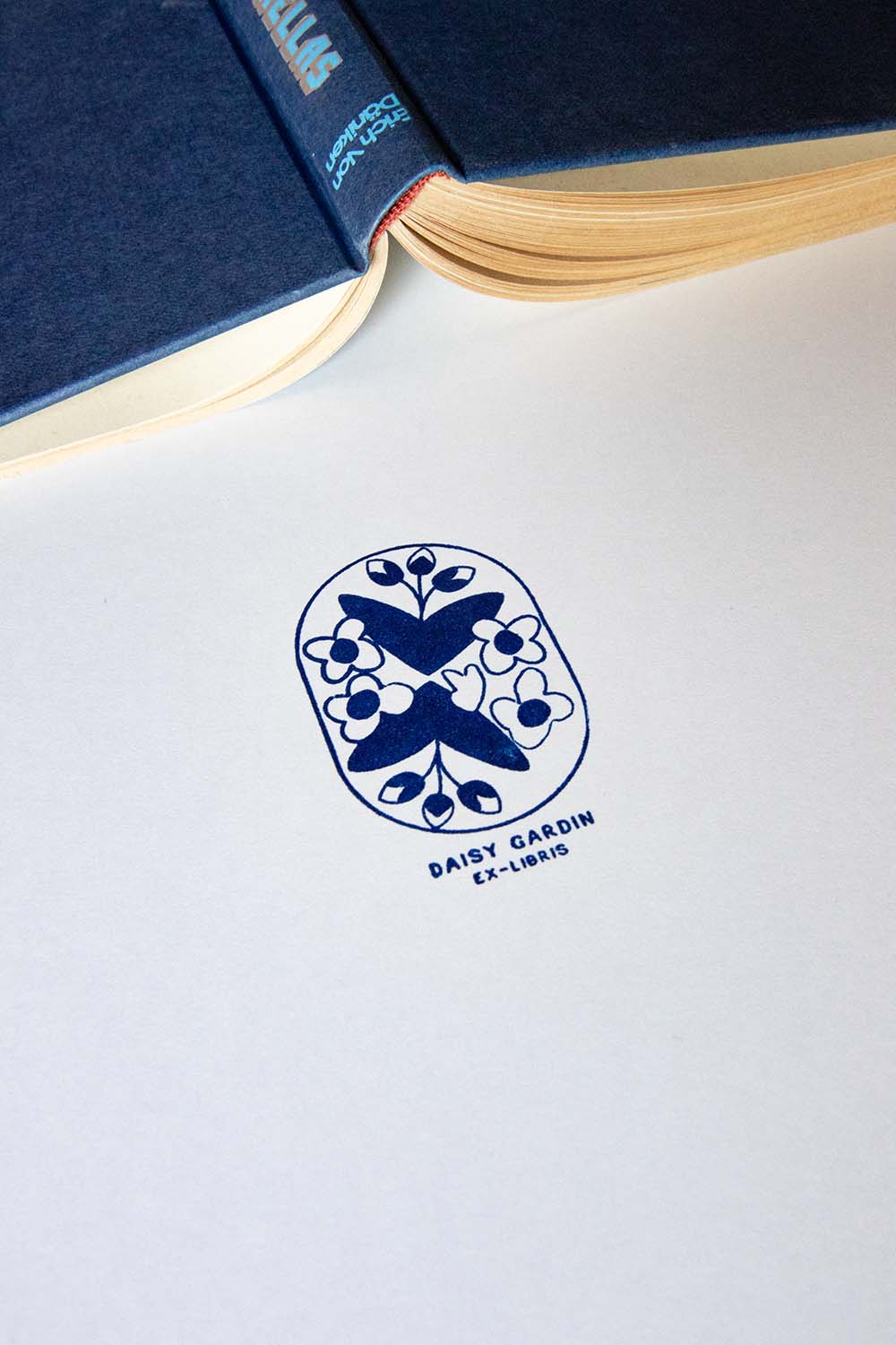 Papel estampado con sello exlibris de un motivo floral enmarcado en un recuadro con esquinas redondas