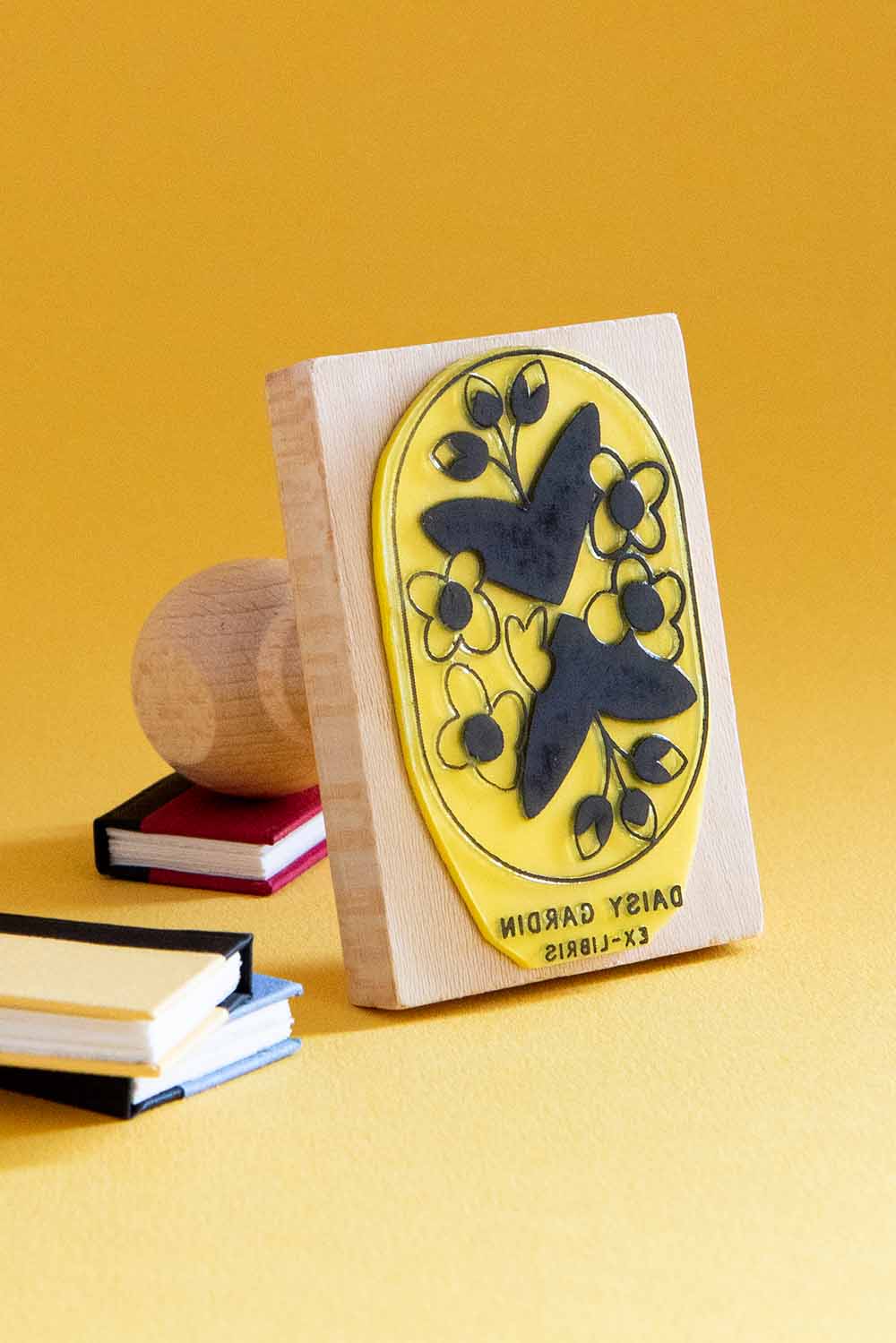 Sello exlibris grabado con un motivo floral enmarcado en un recuadro con esquinas redondas