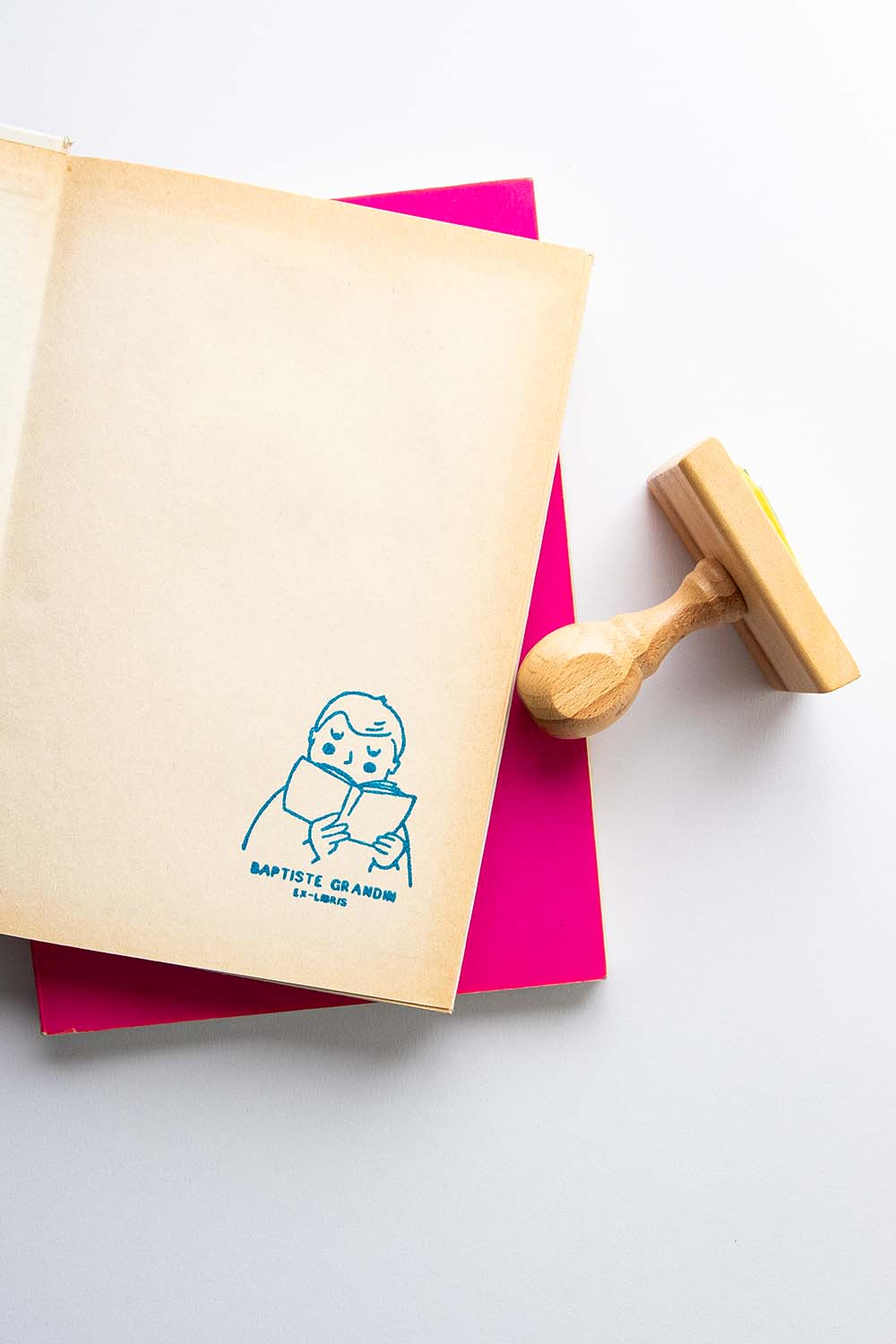 Portadilla de libro estampada con sello exlibris de un niño leyendo y sello