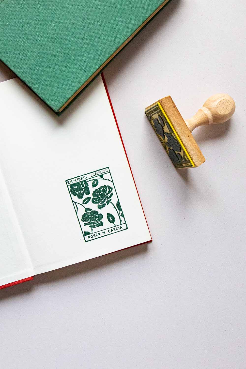 Portadilla de libro estampada con sello exlibris de rosas dentro de un recuadro y sello