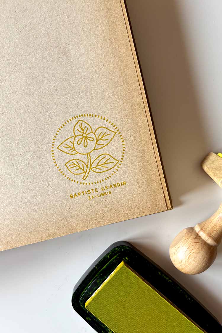 Portadilla de libro estampada con sello exlibris de una flor enmarcada en un círculo y sello